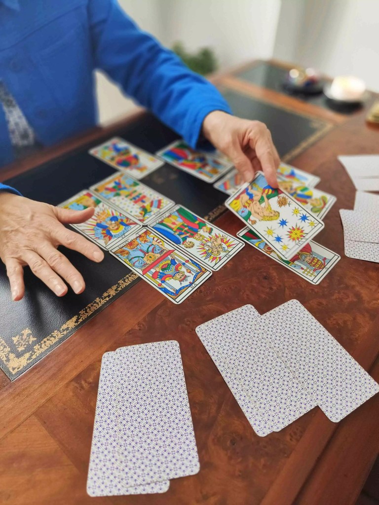 des mains tirent les cartes d'un tarot de marseille pour prédire l'avenir 